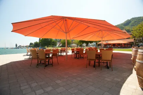 Zwei gekoppelte Zeltschirme überspannen eine Terrasse