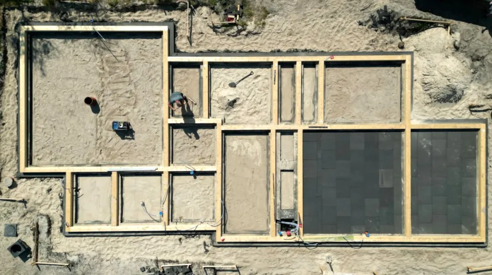 Betonfreies TverstedHouse aus der Vogelperspektive: Gut sichtbar die Streifenfundamente aus Schaumglas sowie Holzbalken für den Wandaufbau. Rechts im Bild: zwei Räume mit ausgelegter Schaumglas-Bodenplatte.