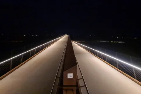 Handlaufsystem LUX GLENDER SAFE - Fußgängerbrücke Buga 2023 in Mannheim | Einseitige symmetrische Beleuchtung der Laufbahn. Ausführung IP65, um ca. 15° gedrehter Handlauf LILLY.