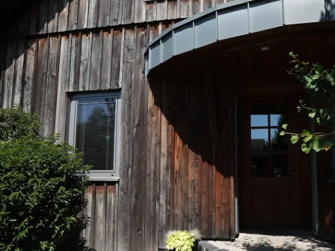 Das Erscheinungsbild der Holzfassade zeigt, dass sie ungeschützt und somit ungleichmäßig verwittert ist.