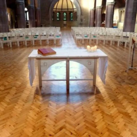 Fertiggestellter Bodenbelag auf dem Lithotherm-System – Altarbereich und Bestuhlung im sanierten Kirchenraum.