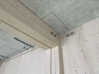 Querträger mit Akustikdecke und bewusst sichtbaren Rohrleitungen