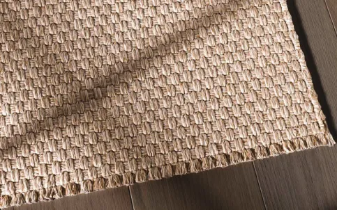 Die Einfassung Natural Border spiegelt durch die genähten Kanten mit offenen Garnenden den mediterranen Lifestyle wieder und meistert robuste Outdoor-Anforderungen.